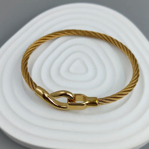 Gold bracelet with clasp on a white and gray background