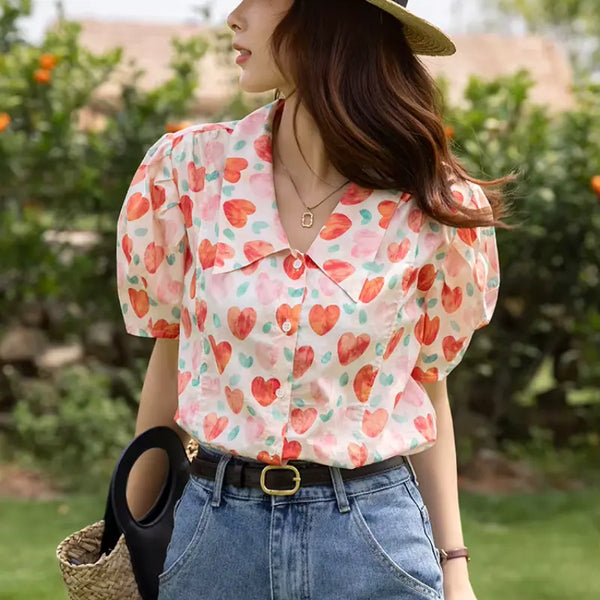 Woman wearing a colorful heart-patterned blouse outdoors