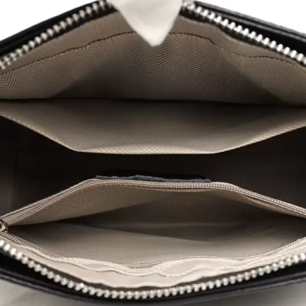 Close-up of a black handbag with a zipper, showing the interior.