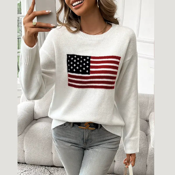 Person wearing a white sweater with an American flag design, sitting on a couch.