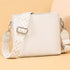 White handbag with a patterned strap on a beige background