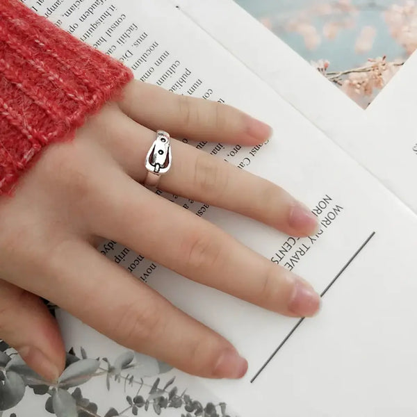 Hand wearing a silver ring with a small pendant on an open book